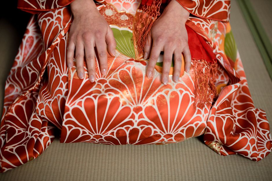 A close-up of a woman's hands resting on a vibrant, traditional Japanese kimono.